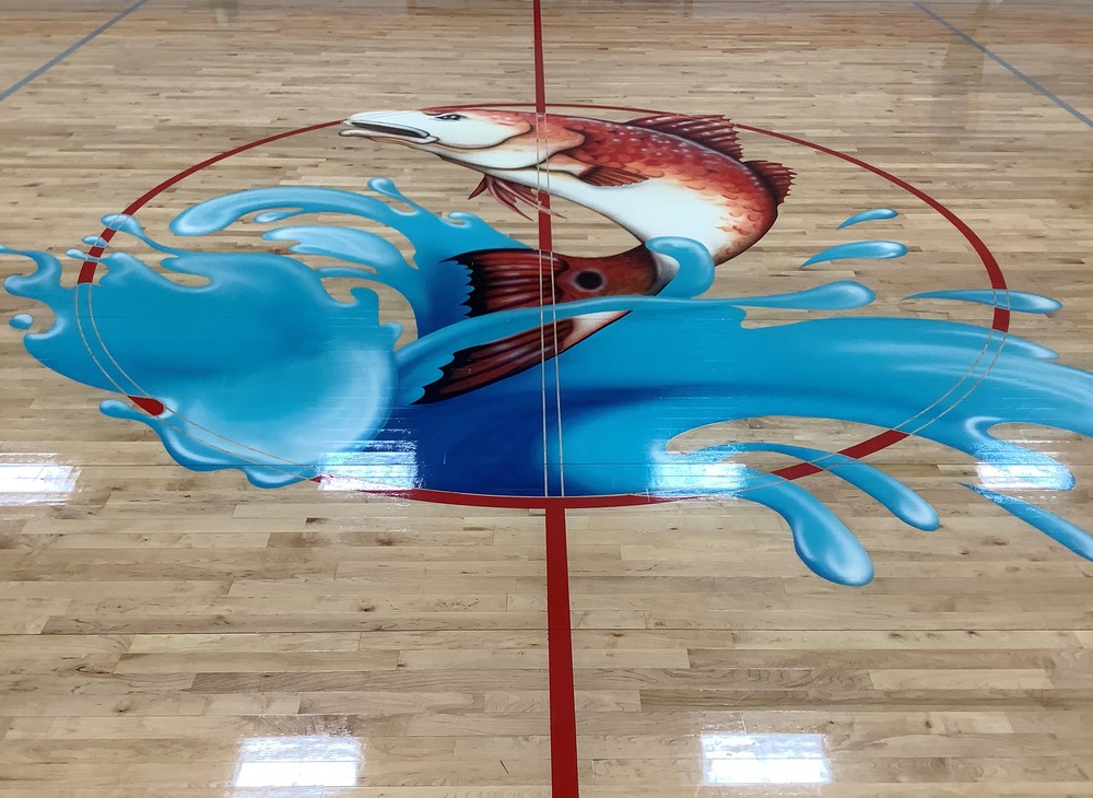 Logo of a fish jumping out of the water on a wooden court